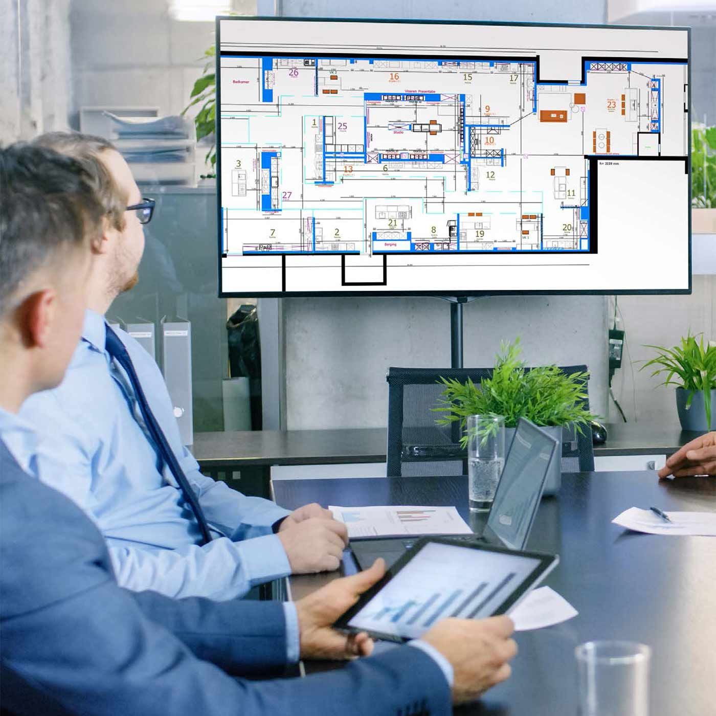 Zakenmensen bespreken bouwplannen die op een groot scherm worden weergegeven.