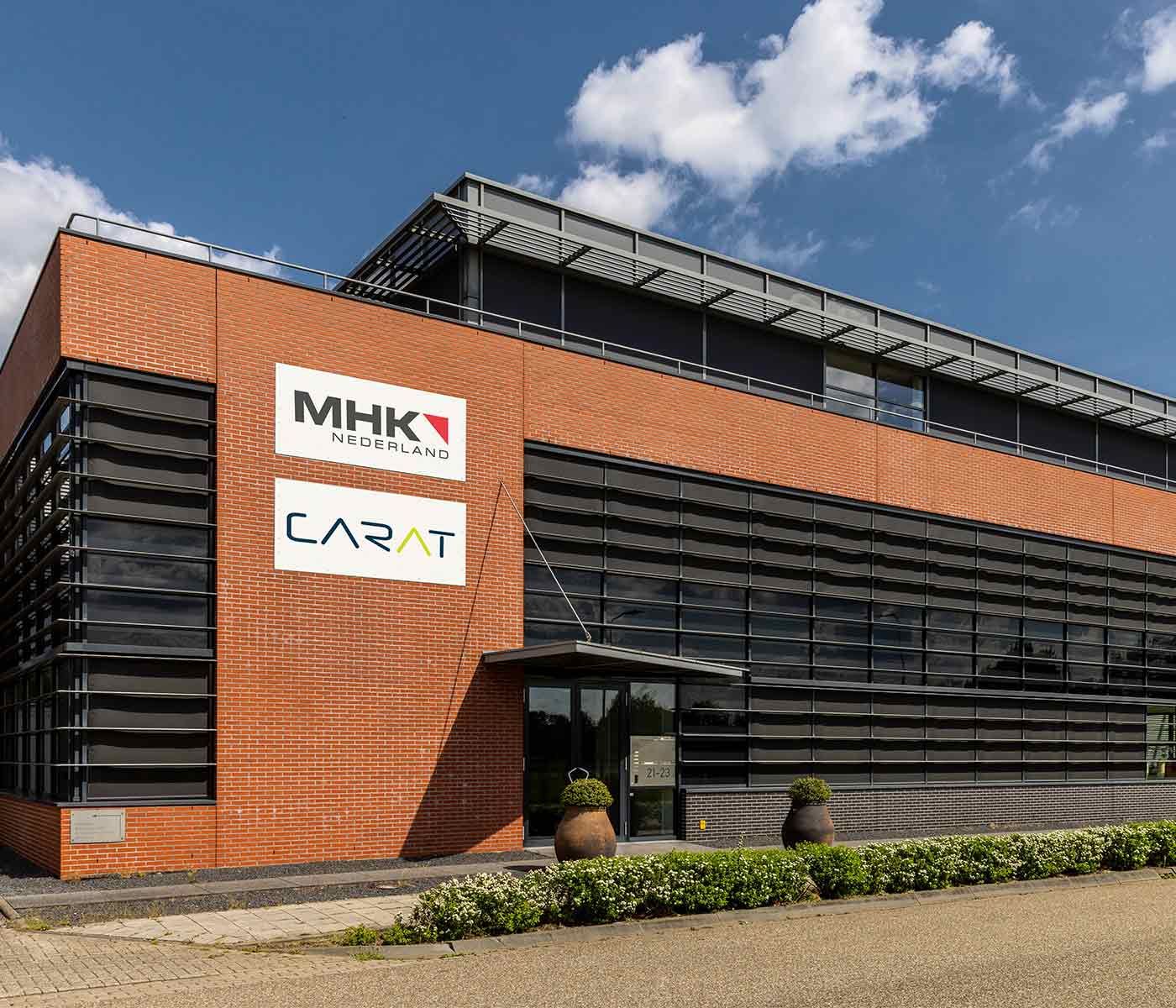 Entree van een modern kantoorgebouw met MHK- en CARAT-logo.