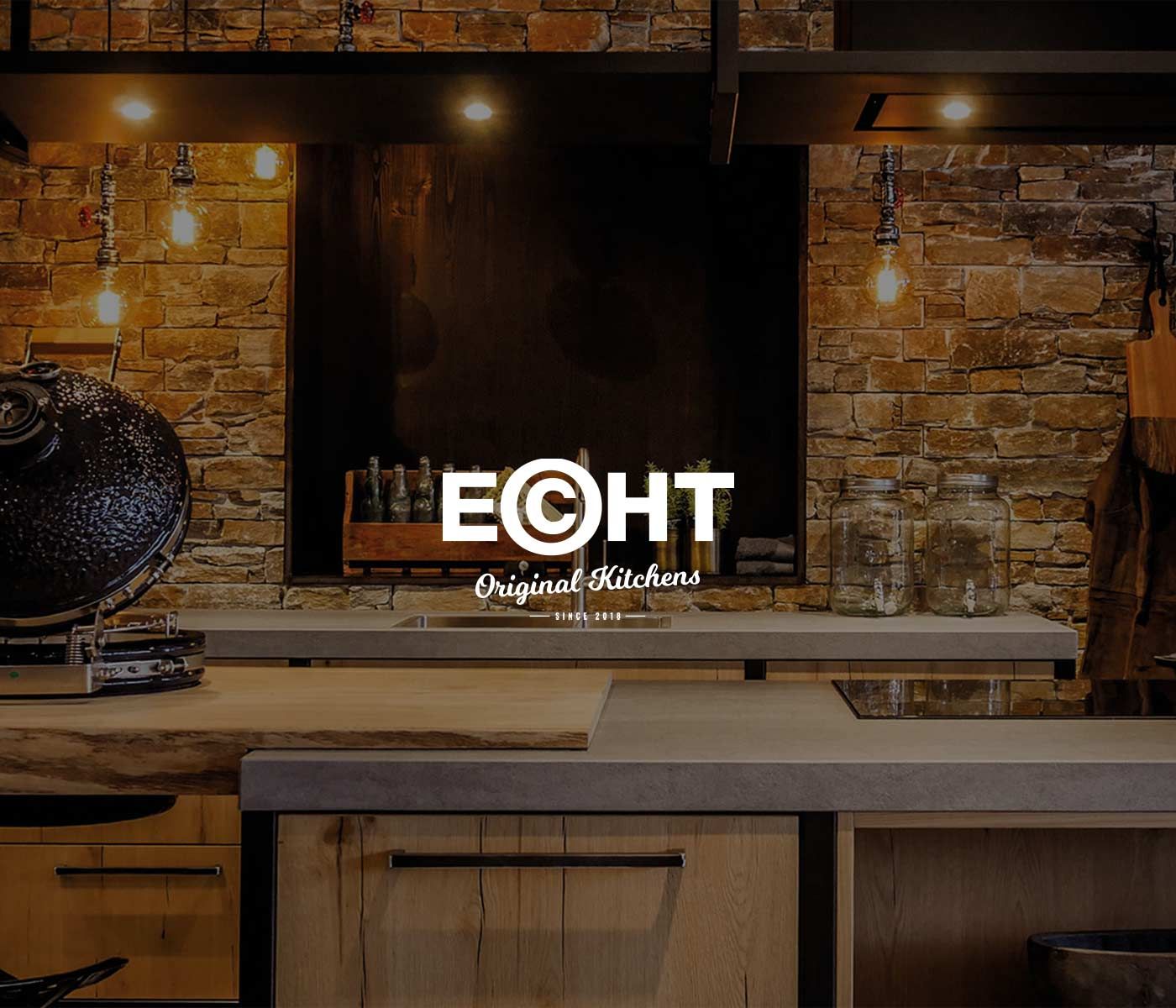 Rustieke keuken met stenen muur en ECHT Original Kitchens-logo.